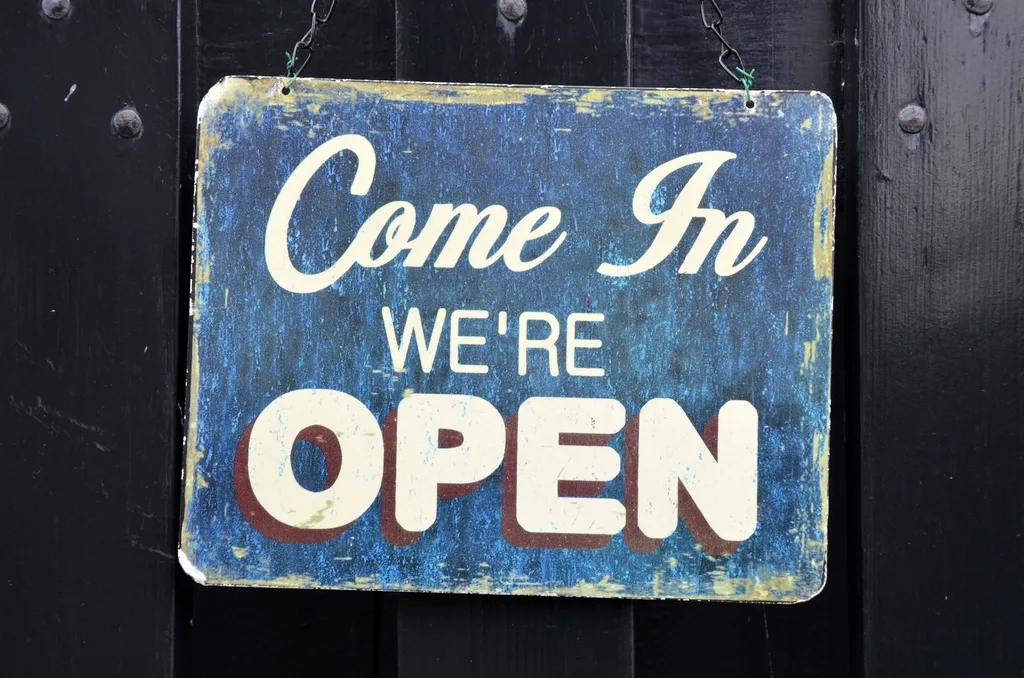 A painted sign on a shop door that reads: Come in, we are open