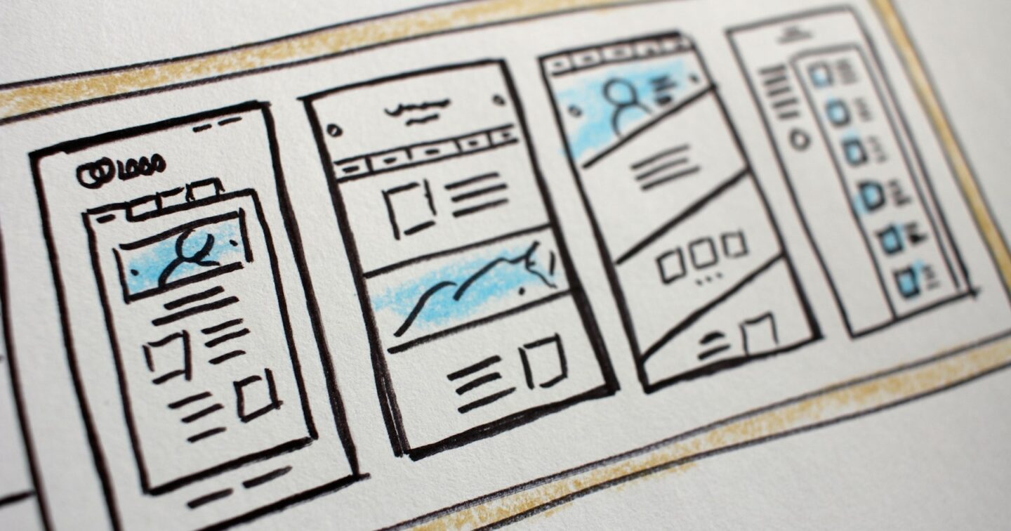 Hand-drawn wireframe sketches of mobile app screens on paper