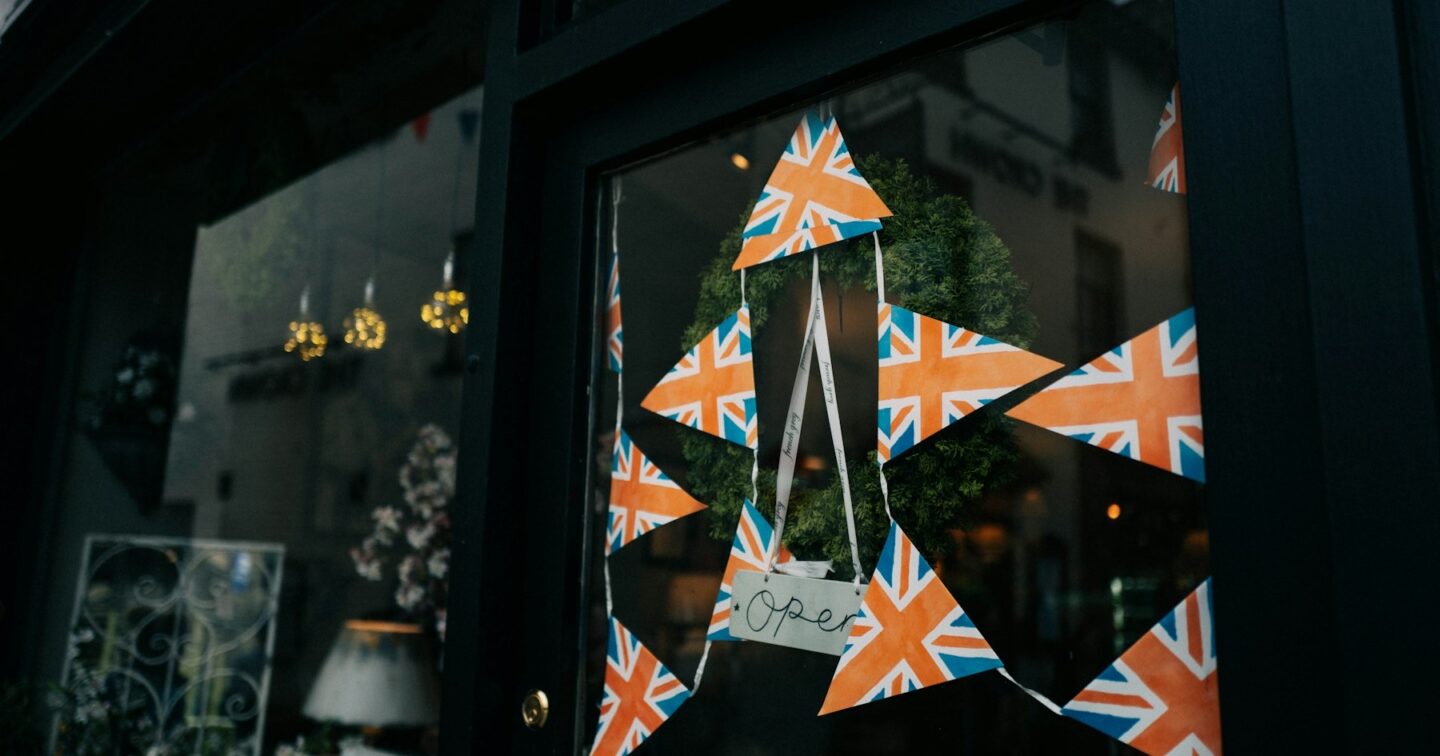 Independent shop window decorated with Union Jack bunting and a handwritten Open sign