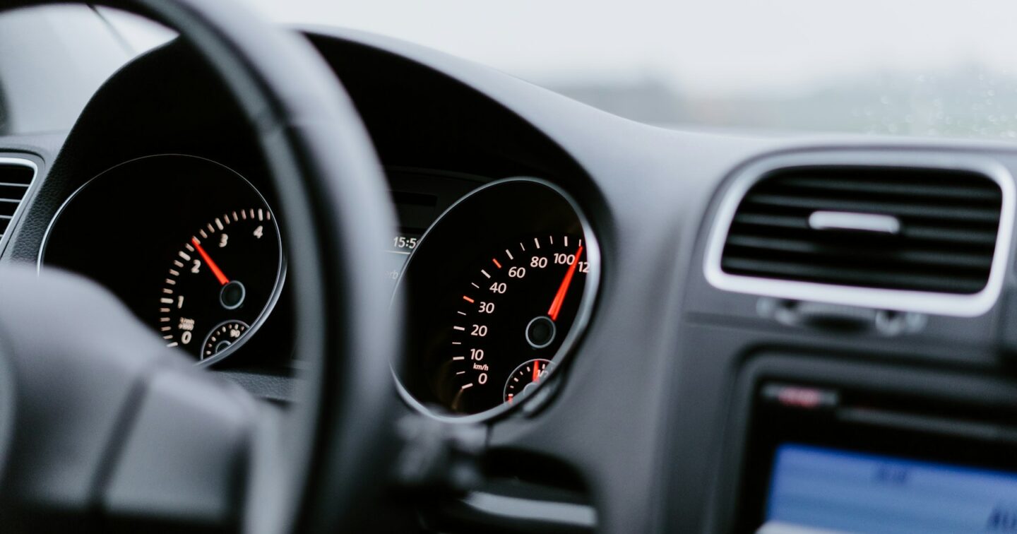 Close-up of a car speedometer and rev counter with the needle near 100, representing website speed