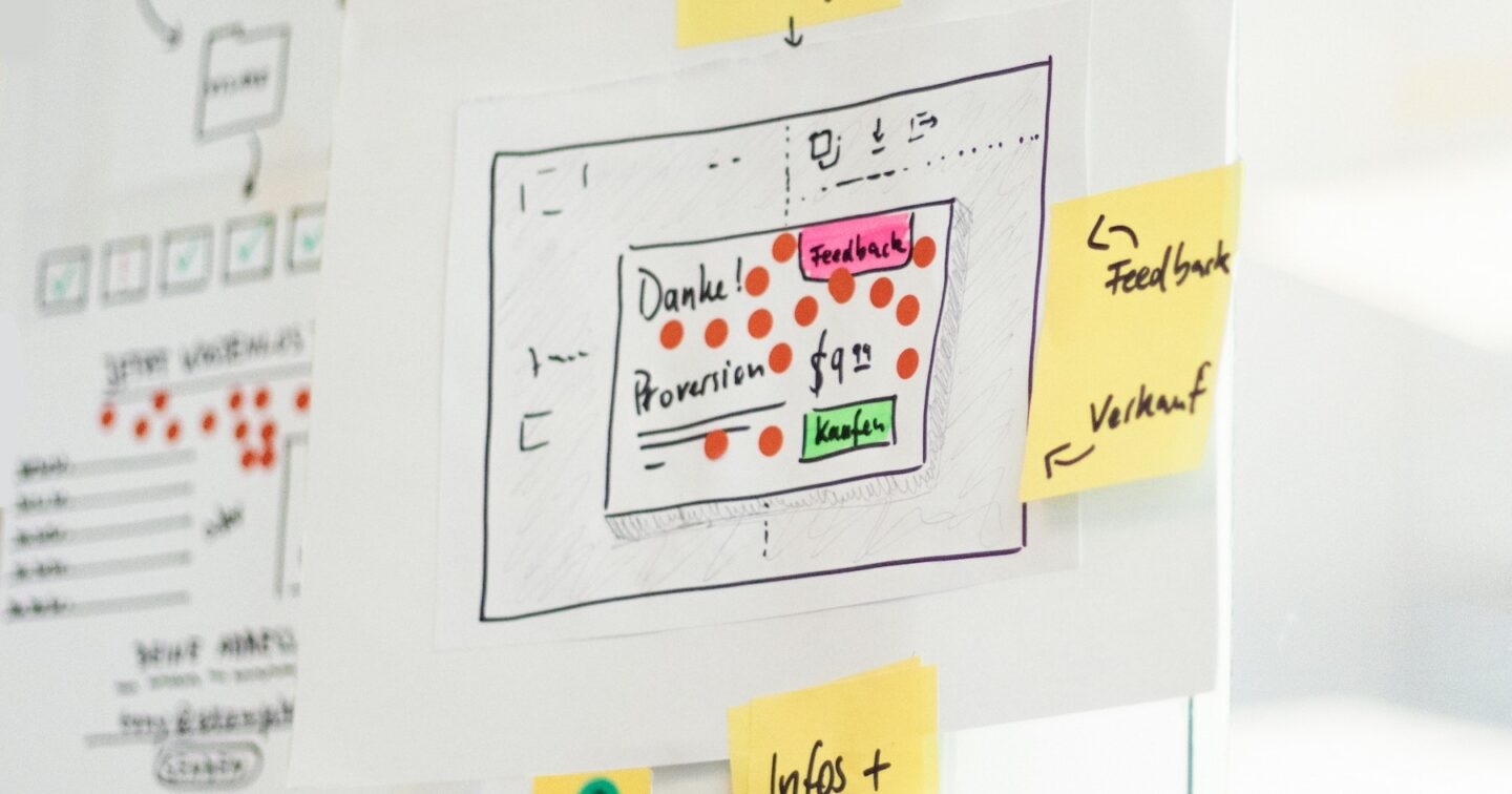 Hand-drawn website wireframes and yellow sticky notes on an office wall during a redesign workshop