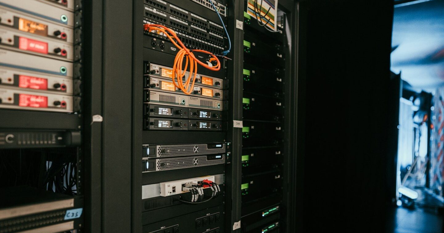 A rack of servers in a server room, with network switches, cables and status lights