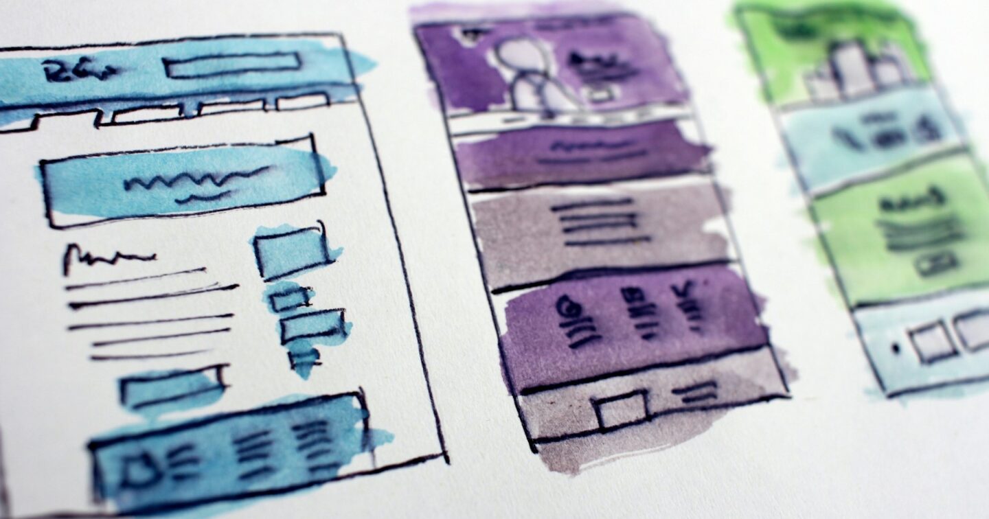 Hand-drawn watercolour wireframes of website page layouts on paper